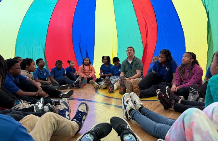  Students in gym class under a colorful parachute.